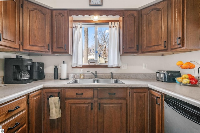 kitchen featuring brown cabinets, light countertops, a sink, and dishwashing machine