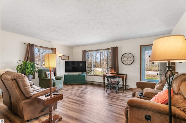 living area featuring a baseboard radiator, plenty of natural light, a textured ceiling, and wood finished floors