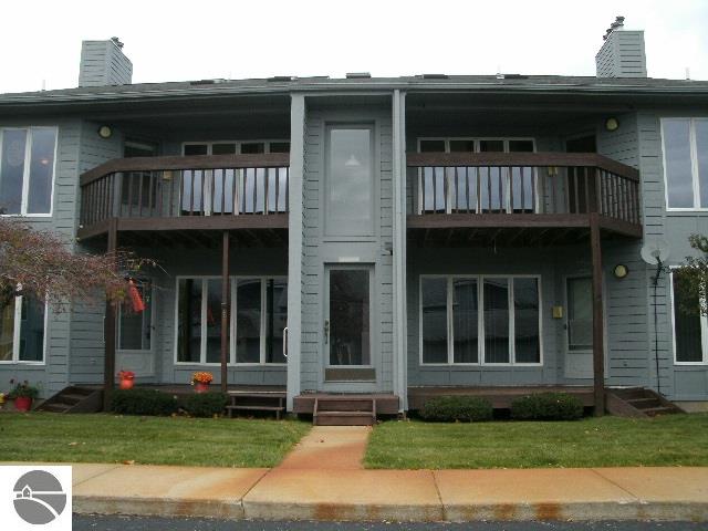 view of front of property featuring entry steps, a chimney, and a balcony