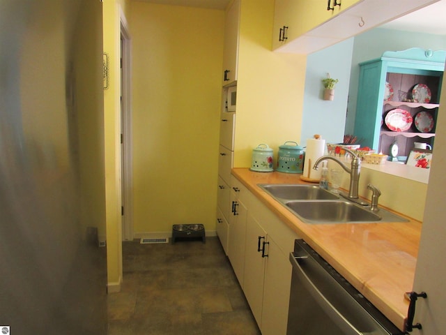 kitchen with light countertops, visible vents, stainless steel dishwasher, white cabinets, and a sink