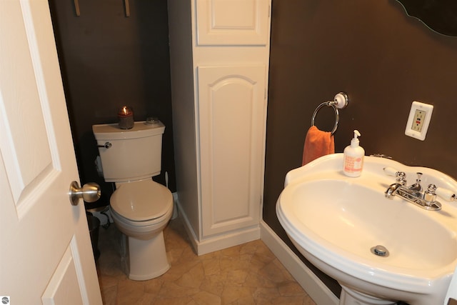 bathroom with a sink, toilet, and baseboards