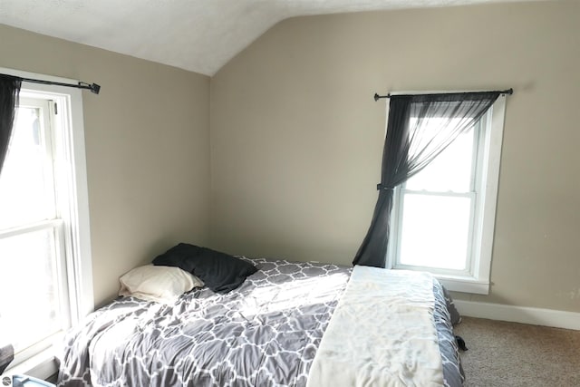 carpeted bedroom featuring multiple windows, vaulted ceiling, and baseboards