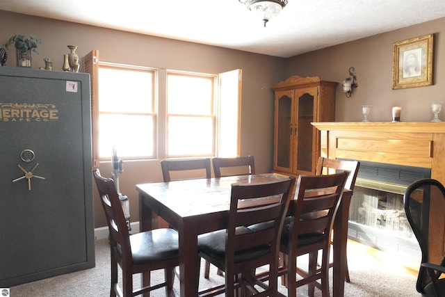 dining area featuring light carpet and a glass covered fireplace