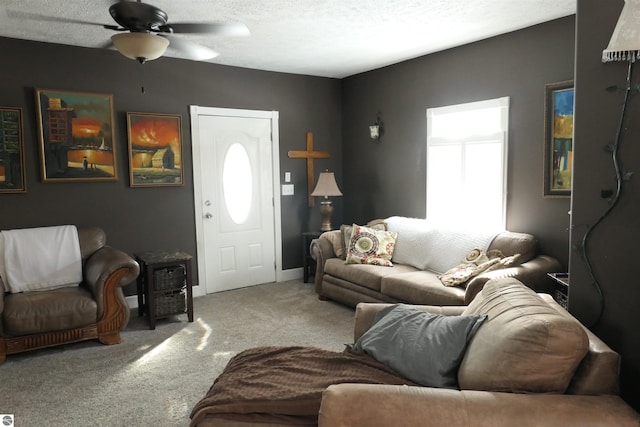 living area with a textured ceiling, baseboards, a ceiling fan, and light colored carpet