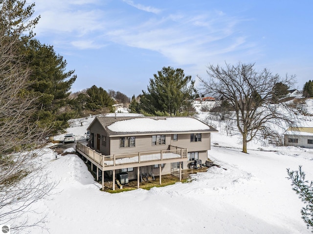 snow covered property featuring an attached garage and a wooden deck