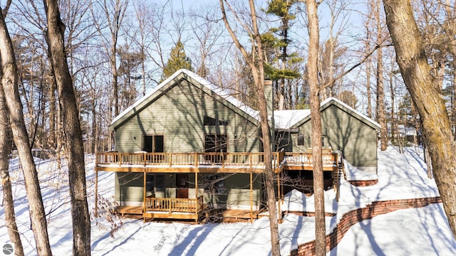 snow covered house featuring a wooden deck