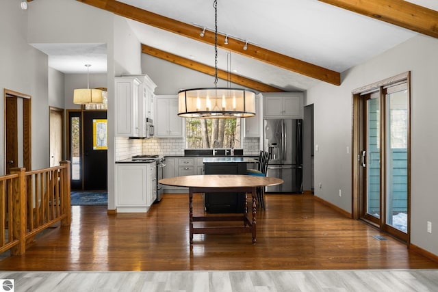 kitchen with a wealth of natural light, appliances with stainless steel finishes, backsplash, and decorative light fixtures