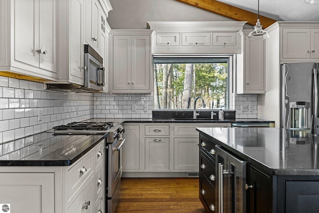 kitchen with pendant lighting, stainless steel appliances, a sink, beverage cooler, and dark cabinetry