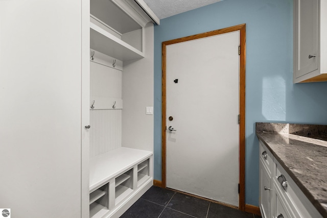 mudroom with a textured ceiling and dark tile patterned floors