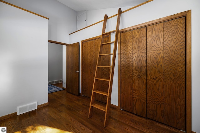 unfurnished bedroom with dark wood-style floors, visible vents, and baseboards