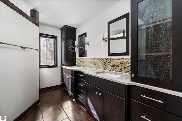 full bathroom with double vanity, baseboards, decorative backsplash, tile patterned floors, and a sink