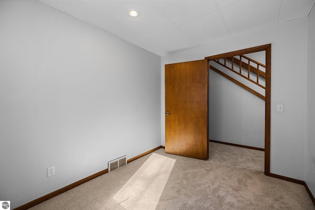 empty room featuring baseboards, visible vents, and light colored carpet