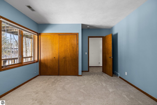 unfurnished bedroom featuring baseboards, visible vents, and light colored carpet