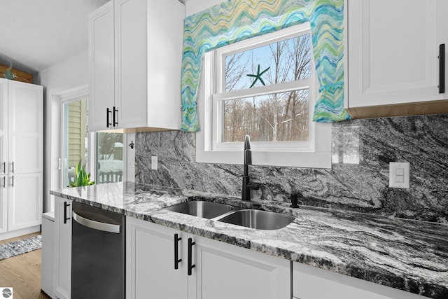 kitchen featuring light wood finished floors, stone countertops, a sink, white cabinetry, and stainless steel dishwasher