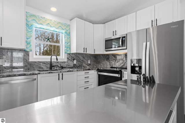 kitchen with appliances with stainless steel finishes, a sink, white cabinetry, and decorative backsplash