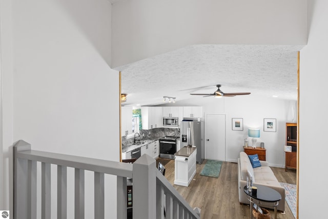 interior space featuring a textured ceiling, wood finished floors, a ceiling fan, and baseboards