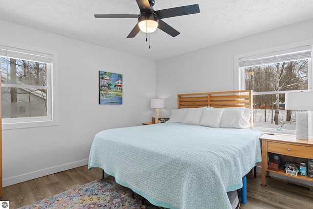 bedroom featuring ceiling fan, a textured ceiling, baseboards, and wood finished floors