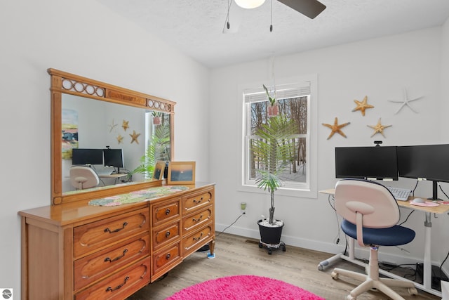 office featuring a textured ceiling, ceiling fan, light wood-style flooring, and baseboards