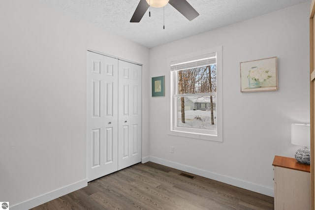 unfurnished bedroom featuring baseboards, a textured ceiling, visible vents, and wood finished floors