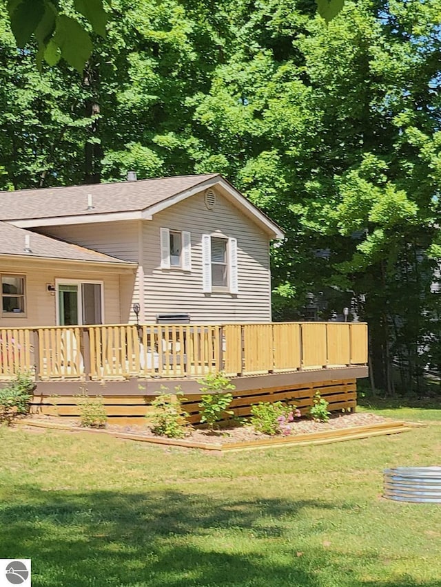 rear view of property featuring a deck and a yard