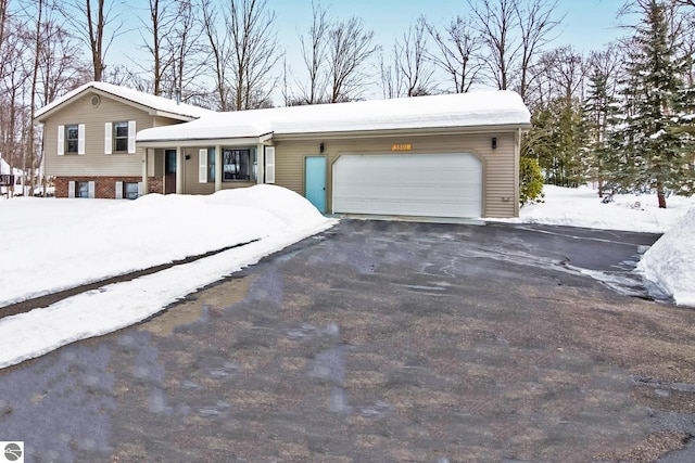 split level home with aphalt driveway, an attached garage, and brick siding