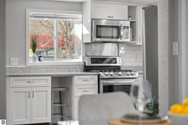 kitchen featuring stainless steel appliances, tasteful backsplash, white cabinetry, and open shelves