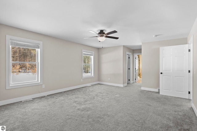 carpeted spare room featuring ceiling fan and baseboards