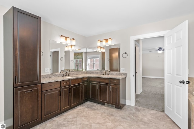 full bathroom with double vanity, a sink, visible vents, and baseboards