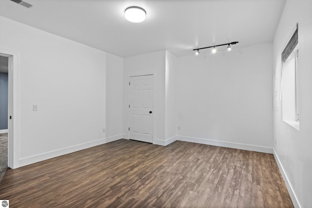 spare room featuring visible vents, baseboards, and dark wood-type flooring