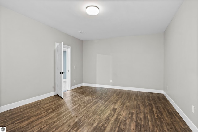 unfurnished room featuring visible vents, baseboards, and dark wood-type flooring