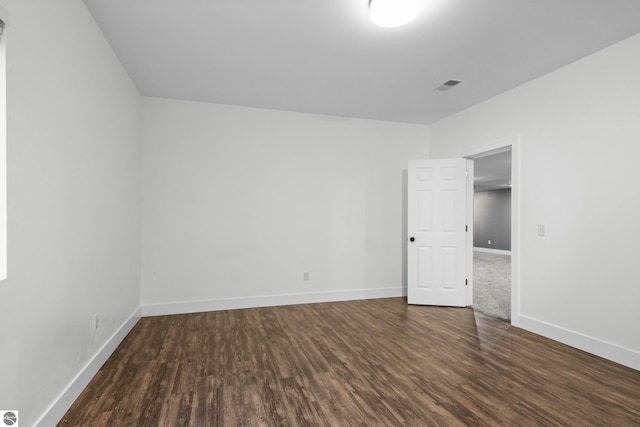 unfurnished room featuring baseboards, visible vents, and wood finished floors