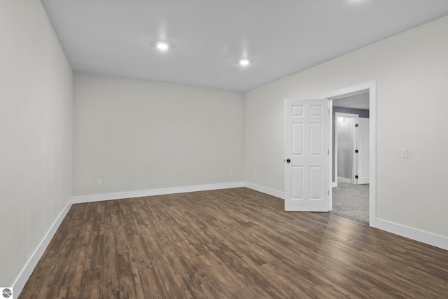 empty room with dark wood-type flooring, recessed lighting, and baseboards