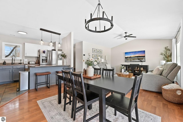 dining room with a ceiling fan, lofted ceiling, and wood finished floors