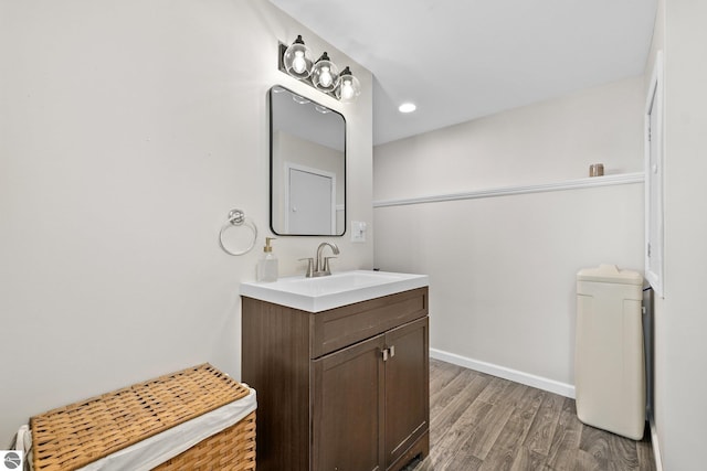 bathroom with recessed lighting, vanity, baseboards, and wood finished floors