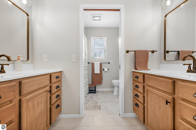 full bath featuring two vanities, tile patterned flooring, a sink, and toilet