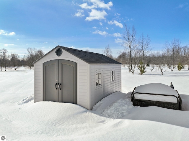 snow covered structure with an outdoor structure and a storage unit