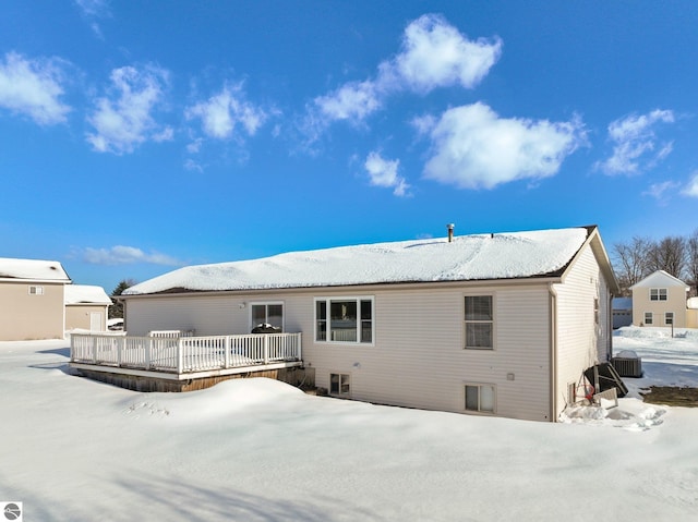 snow covered house featuring central air condition unit and a deck