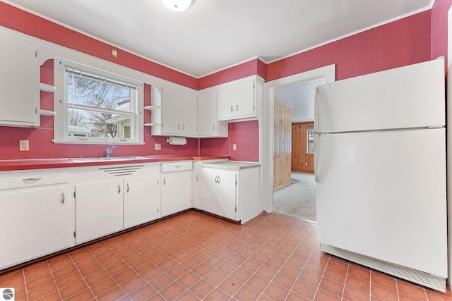 kitchen featuring open shelves, a sink, freestanding refrigerator, and white cabinetry
