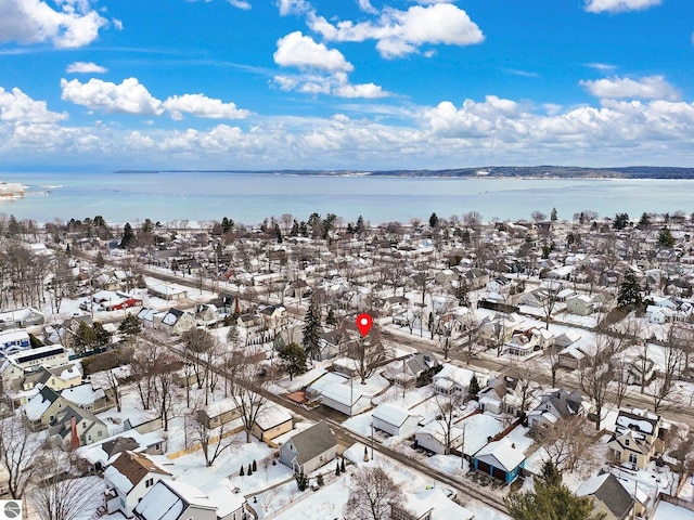 snowy aerial view featuring a water view and a residential view