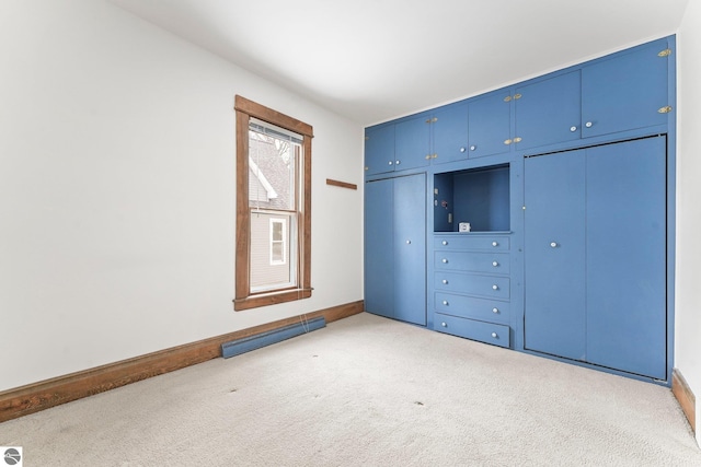 unfurnished bedroom with baseboards, baseboard heating, multiple closets, and light colored carpet