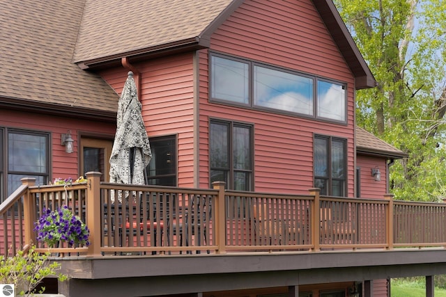 rear view of property with a deck and roof with shingles