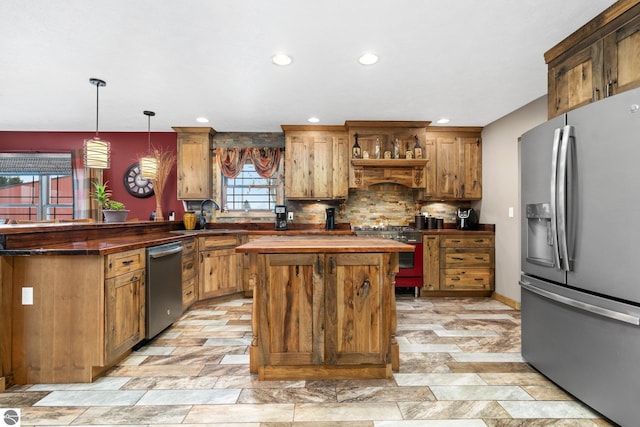 kitchen with a peninsula, a sink, appliances with stainless steel finishes, backsplash, and pendant lighting