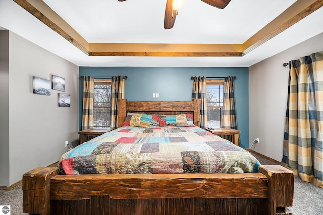 bedroom featuring a tray ceiling, carpet flooring, and multiple windows