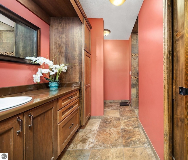 hall with stone finish floor, a sink, and baseboards