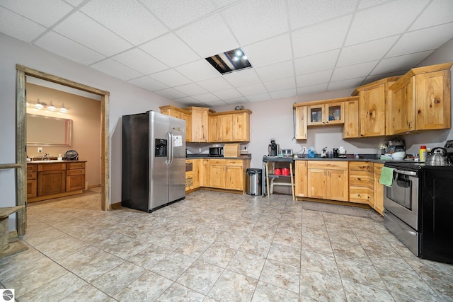 kitchen with stainless steel appliances, a paneled ceiling, dark countertops, and glass insert cabinets