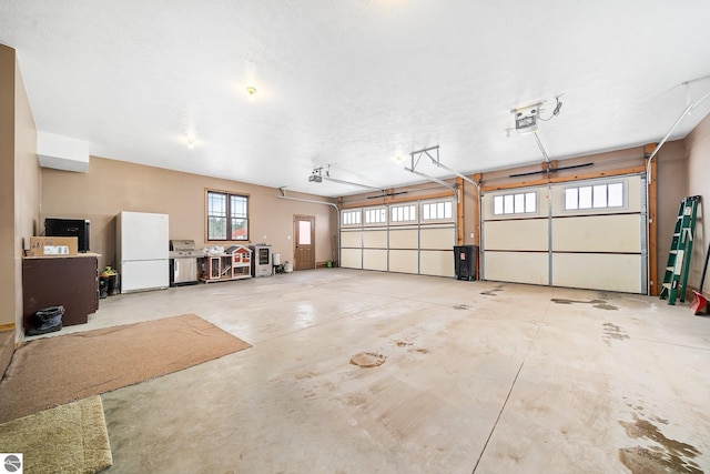 garage featuring freestanding refrigerator and a garage door opener