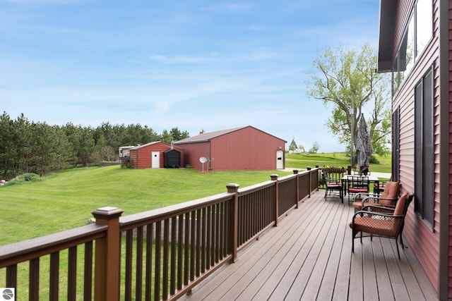 wooden terrace featuring an outbuilding, a yard, and outdoor dining space