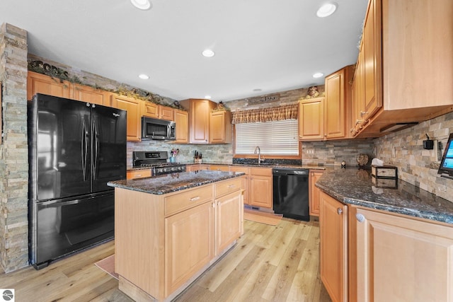 kitchen featuring black appliances, dark stone countertops, a sink, and a center island