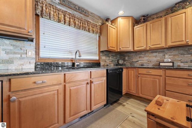 kitchen featuring dishwasher, backsplash, dark stone countertops, light wood-type flooring, and a sink