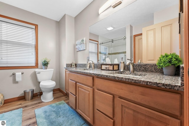 bathroom featuring toilet, a shower stall, a sink, and wood finished floors